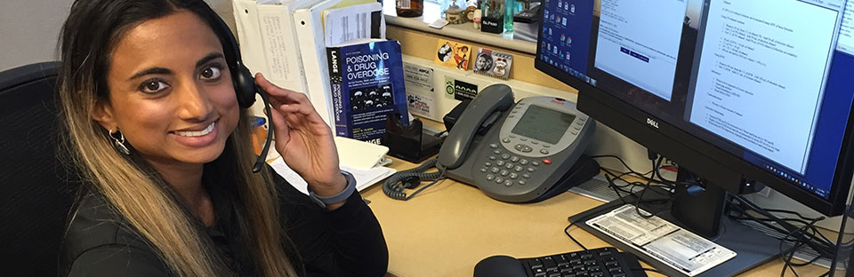 Registered pharmacist answers phone calls using her headset as she looks at the camera.