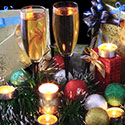 Two glasses of champagnes surrounded by holiday bulbs and garland.