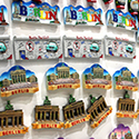 Colorful magnets displaying the Berlin city name are photographed against a solid beige surface.