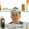 Young boy looks into open medicine cabinet with a wide array of medicines and medical supplies available out in the open.