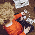 Female child sitting on floor surrounded by open bottles and packets of medication.