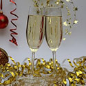 Two champagne glasses clinked together against a backdrop of red and gold streamer ribbons.