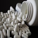 white pills sitting next to open medicine bottle