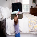 Child reaching into an open suitcase on a bed with medicine in it
