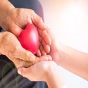 A caregiver and adult or older adult holding hands together with a heart