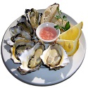 Plate of oysters with sauce and lemon wedges